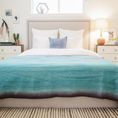 A bedroom in an apartment with a double bed and beside cabinets, and a green quilt on the bed.