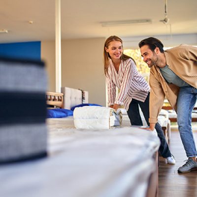 A young couple is choosing bedding at a bed, mattress and pillow store. Everything for a comfortable sleep.